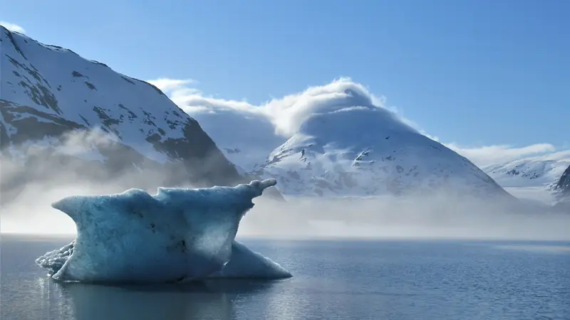 Illustrative photo: an iceberg on Portage Lake below snow-covered peaks