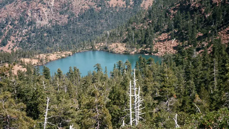 Illustrative photo: a small blue lake in a forested basin below a rocky ridge